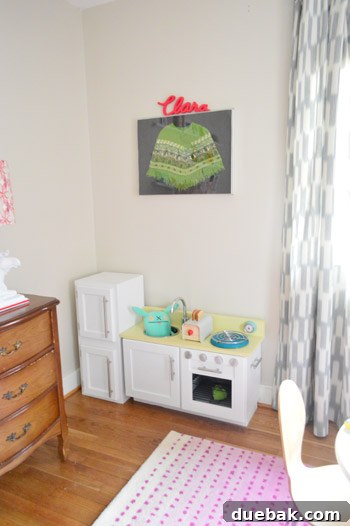 Clara's personalized name plaque above the play kitchen
