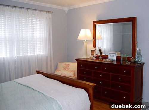 bedroom-one Fully transformed master bedroom with coral slipper chair, wood floors, and fresh decor