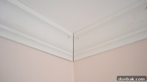 Mastering Crown Molding Installation 17 Corner of crown molding installed against ceiling with small seam at corner to be caulked