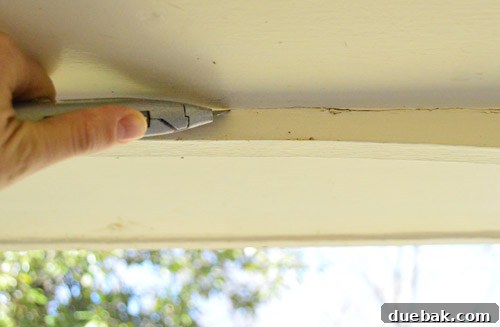 Refreshing Your Porch: Taking Down Scalloped Trim and Repairing Columns 4 A utility knife scoring the paint line along the scalloped trim, preparing for clean demolition.