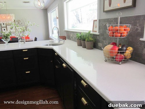 Modern kitchen showcasing white upper cabinets, dark gray lower cabinets, quartz countertops, and limestone backsplash.