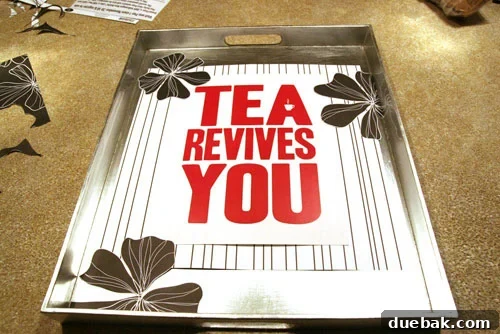 Melinda carefully arranging decorative paper and a 'Tea Revives You' slogan on a custom tea tray for a DIY project.
