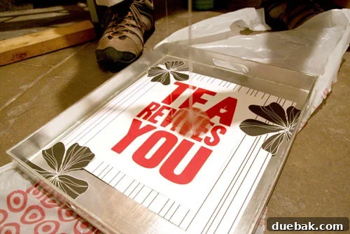 Close-up view of a custom tea tray with beautifully arranged striped and floral scrapbook paper and a 'Tea Revives You' slogan adhered.