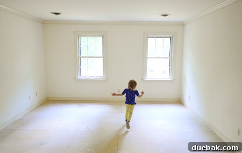 little girl running in empty room with no carpet