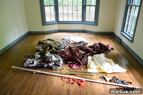 Farewell, Faded Curtains 7 A large pile of removed floral curtains on the floor, marking the successful completion of the task.