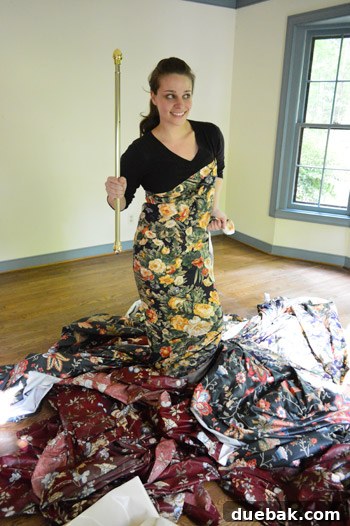 Farewell, Faded Curtains 9 A person playfully holding a curtain rod like a scepter, with the floral curtains draped around them.