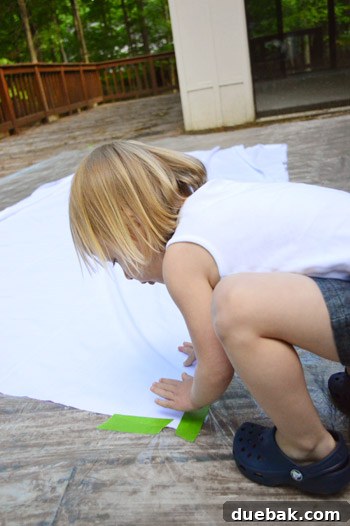 Close-up of the cotton fabric taped down on a drop cloth on a deck, ready for painting.