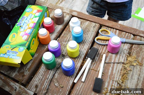 Various colors of Crayola Kids' Paint pots laid out on the drop cloth next to the fabric.