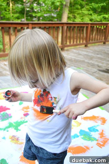 Clara standing in front of the wet, painted fabric, with some paint on her shirt.