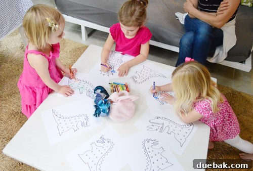 Dragon's Lair Birthday Bash 18 Children happily coloring dragon print-out sheets at a toddler's birthday party, with crayons scattered on the table.