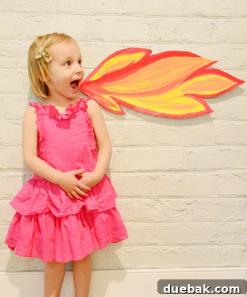 Dragon's Lair Birthday Bash 4 A young girl joyfully posing next to a DIY fire-breathing dragon photo cut-out at her dragon birthday party.