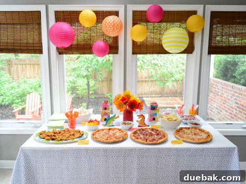 Dragon's Lair Birthday Bash 6 A vibrant dragon birthday party food spread featuring pizza, fruit, and snacks, decorated with colorful paper lanterns.