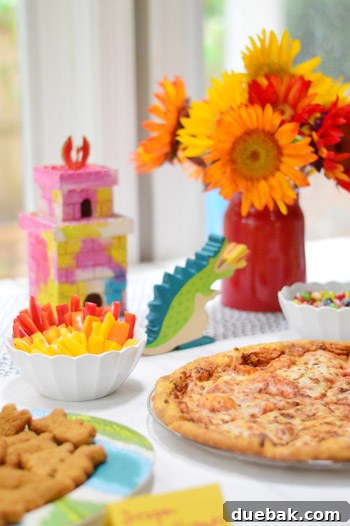 Dragon's Lair Birthday Bash 8 A close-up of dragon birthday party food, featuring pizza slices, colorful peppers, and painted castles with dragon figurines.
