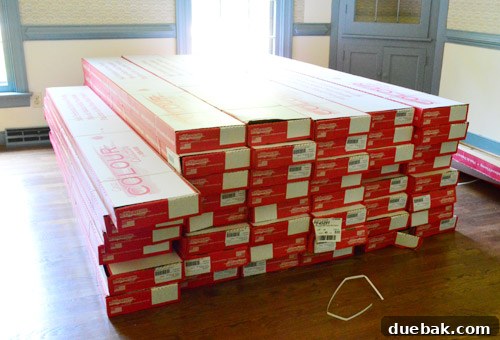 Stacked boxes of hardwood flooring next to a house