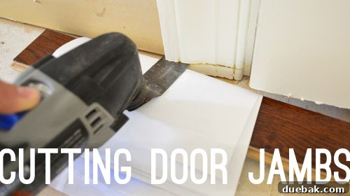 A Dremel tool being used with a guide to cut the bottom of a door jamb, allowing space for new flooring to slide underneath.