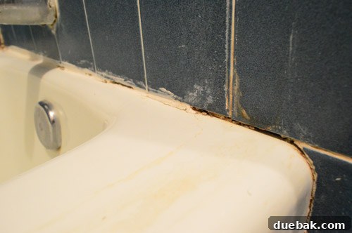 Ditch Your Outdated Sliding Shower Door 12 Close-up of old, damaged caulk around tub