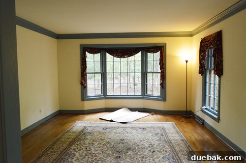 Initial view of an empty, unfurnished room with a large bay window, destined to become a home office.