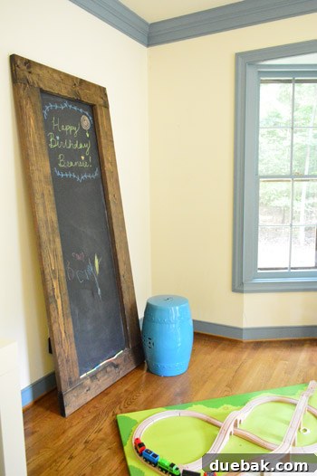 Corner of the office featuring a large chalkboard leaning against the wall, covered in children's drawings.