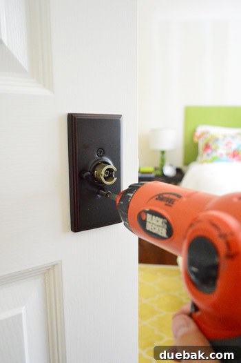 New doorknob installation begins, showing the initial drilling process on an existing door