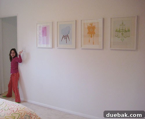 Olivia, a young girl, proudly posing in her room with her new retro art prints featuring a phone, chandelier, cuckoo clock, and vintage chair adorning a white wall.