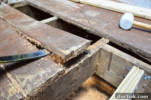 Prying up deck board with crowbar