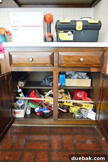 First Chapter 30 Kitchen cabinet filled with a variety of tools, illustrating ongoing renovation.