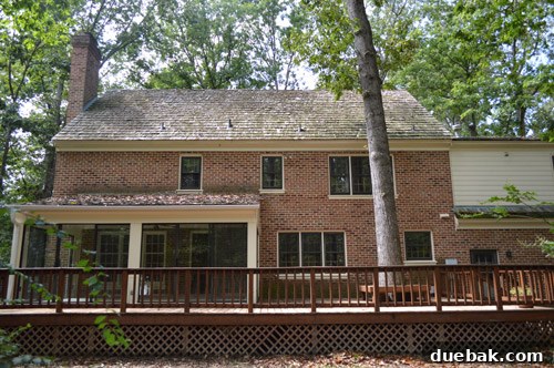 Before photo of the back of the house, showing uneven siding colors