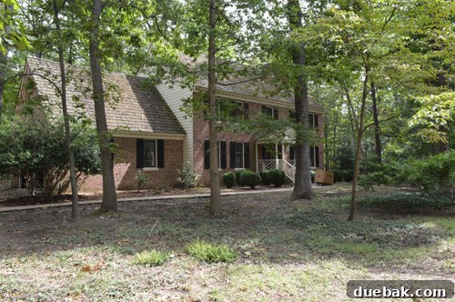 Before photo of the house exterior with old, faded paint and brown tones