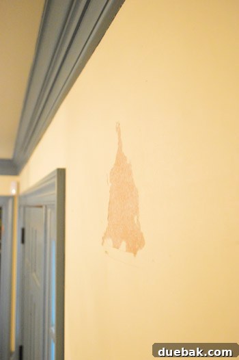 Damaged drywall after wallpaper removal, showing torn paper