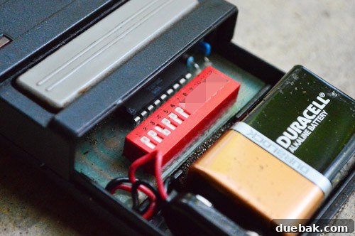 Close-up of dip switches inside an old garage door remote, partially obscured for security