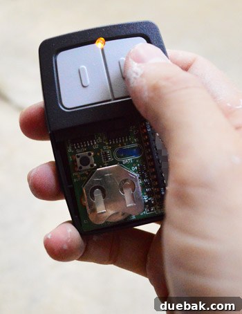 Hand holding the programmed Clicker universal remote, pressing a button