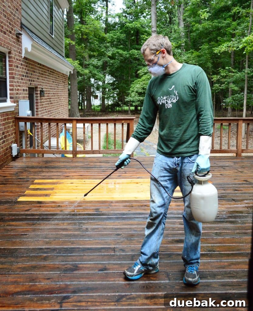 A person using a pump sprayer to apply a deck cleaner and brightener solution to a freshly stripped wood deck