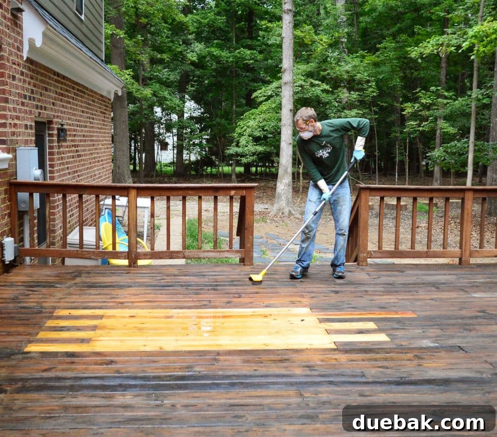 A person scrubbing a wood deck with a deck brightener and cleaner solution, working it into the wood