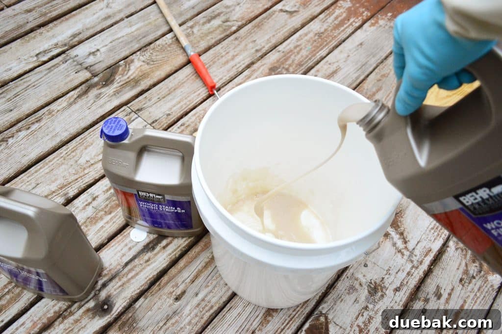Person pouring deck stripping chemical into a bucket, preparing for application