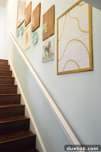 Townhouse Takeover: Unleashing Cozy Creativity 15 Third-floor stairwell featuring serene Olympic Oasis blue walls and unique DIY art with wood planks and wired vintage bottles.