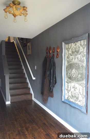 Townhouse Takeover: Unleashing Cozy Creativity 3 Elegant entryway featuring Sherwin Williams Gauntlet Gray walls, rich wood floors, and repurposed vintage decor.
