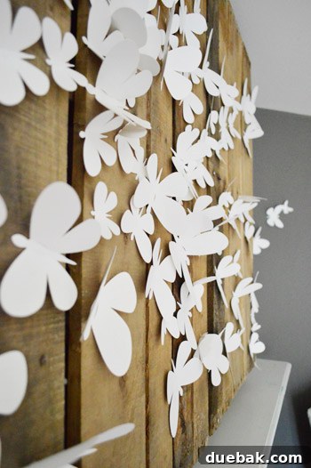 Townhouse Takeover: Unleashing Cozy Creativity 5 Creative fireplace decor with delicate paper butterflies pinned to a rustic pallet, concealing a TV opening.