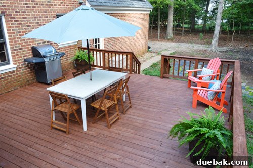 Patio furniture including a table and chairs placed on a newly stained deck, highlighting the improved outdoor living space.