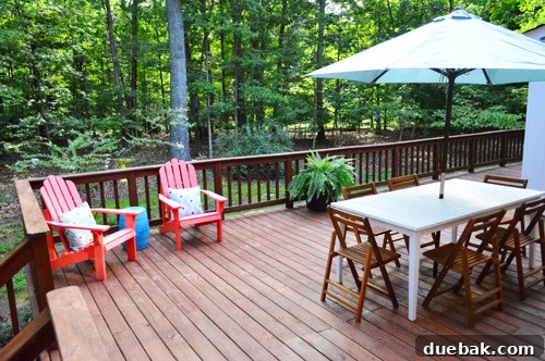 Newly decorated deck with planters and an umbrella, making the space feel less sparse and more inviting after staining.