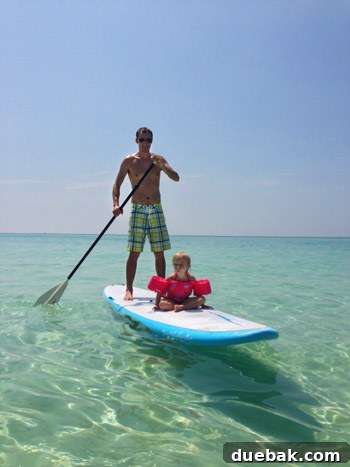 Adult on a stand-up paddleboard in Destin's calm Gulf waters with another person in background
