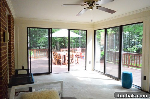 Sunroom with carpet removed and initial furniture placement, showing early changes