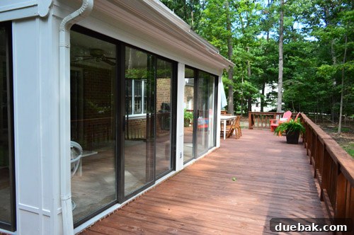 Exterior view of the sunroom showing the surrounding deck and old, stuck sliding doors