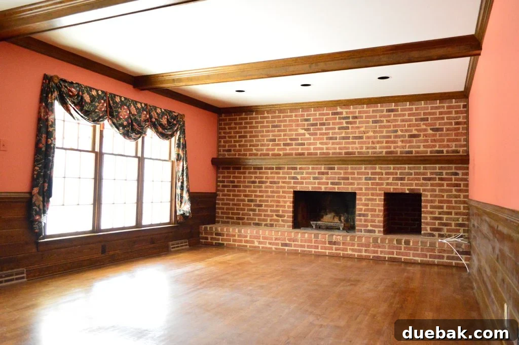 DIY Whitewashing: Transform Your Brick Fireplace 14 A dated 1980s living room with a dark brick wall fireplace, prominent wood beams, and red salmon-colored walls before renovation.