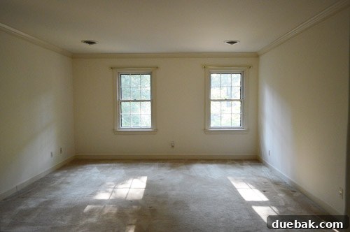 Overview of the transformed master bedroom showcasing new dark paint, updated flooring, and crisp white trim