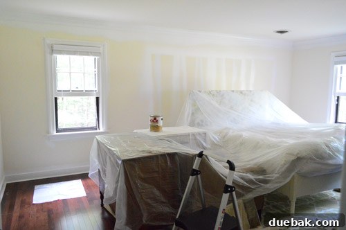 Master bedroom furniture carefully covered with protective drop cloth during painting preparation