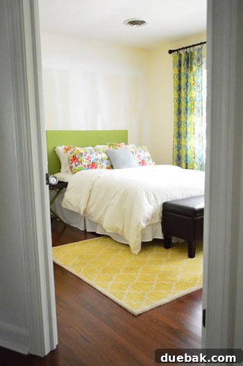 Guest bedroom / craft room with new hardwood floors, painted trim, existing furniture, and hung curtains, stripey walls visible.