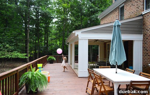 Another view of the renovated back deck and house exterior, showcasing the fresh paint and deck stain.