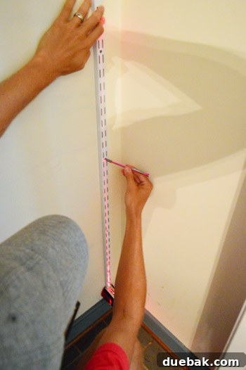 From Coat Closet To Toy Central 5 Installing the first vertical track for the adjustable shelving system, using a laser level for precision.