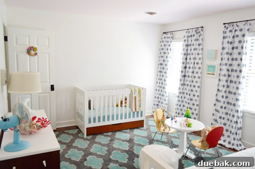 View from the closet into Clara's room, showing the crib area and a blank wall awaiting future art or furniture.