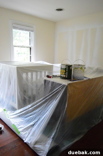 Clara's room undergoing painting preparation, with furniture moved to the center and protected by dropcloths.